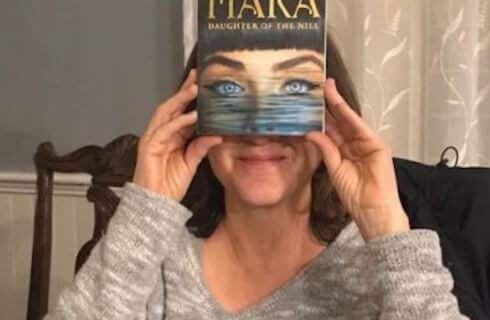 A woman holding a book that is covering her face, with a picture of a woman's face on the book.