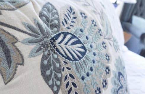 Decorative white pillow with blue, grey and and white beaded embroidery